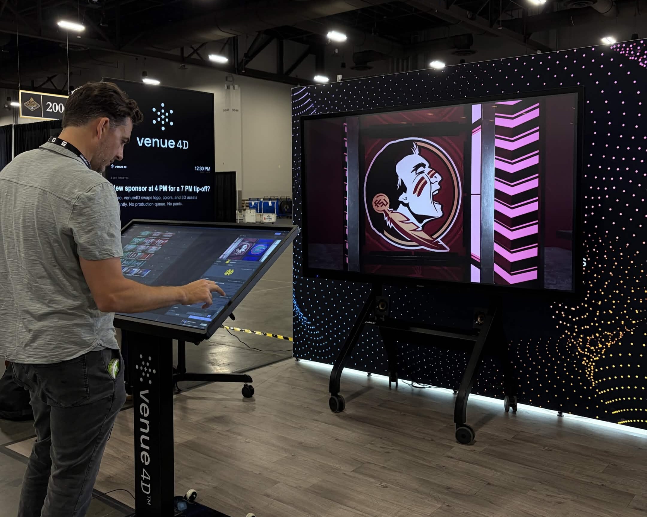 A man interacts with a large touch screen podium labeled 