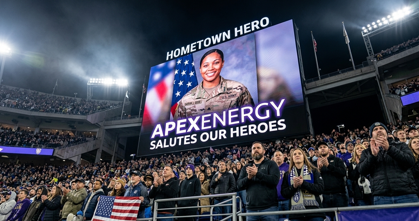 A powerful low-angle shot from inside a crowded football stadium at night, looking up at a giant jumbotron. The screen displays a 